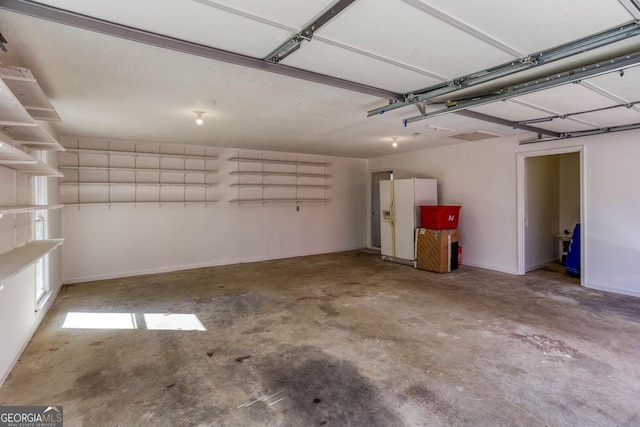 garage featuring baseboards and white fridge with ice dispenser