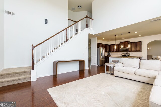 living area with visible vents, arched walkways, dark wood-type flooring, and stairs