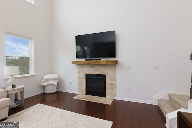 living area with baseboards, a brick fireplace, wood finished floors, and stairs