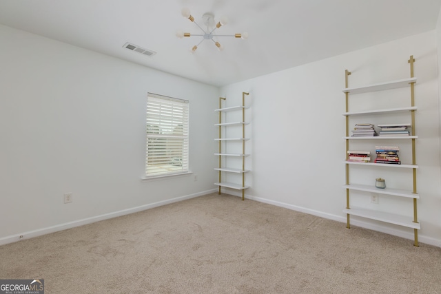 spare room with a notable chandelier, carpet flooring, baseboards, and visible vents