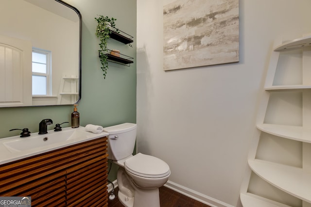 bathroom with baseboards, toilet, wood finished floors, and vanity