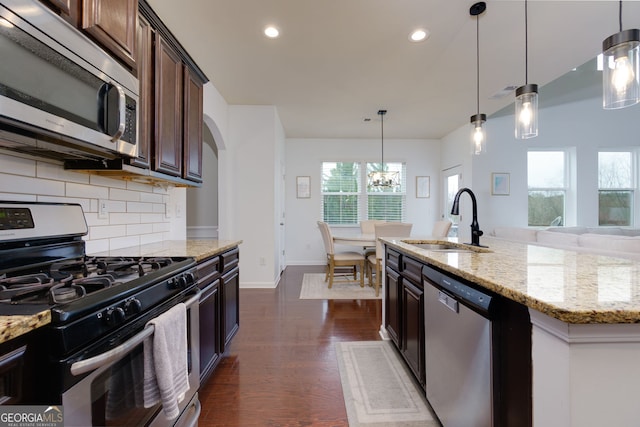 kitchen with a sink, light stone counters, backsplash, and appliances with stainless steel finishes