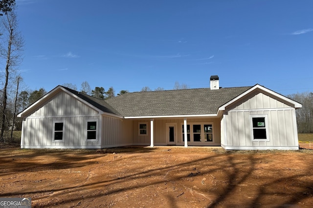 rear view of house featuring a shingled roof and board and batten siding