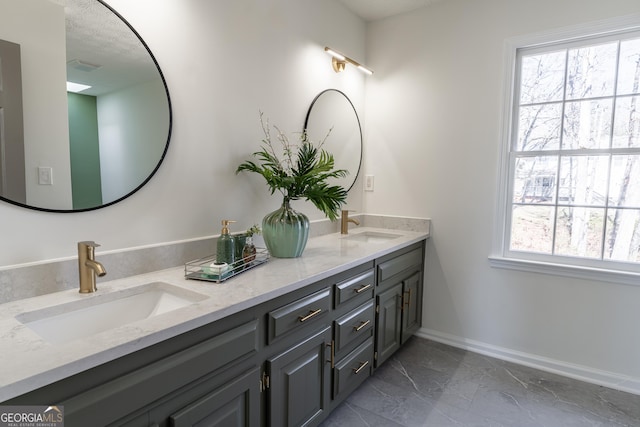 bathroom with marble finish floor, a sink, baseboards, and double vanity