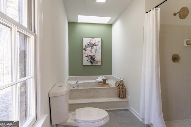 full bath with a wealth of natural light, a skylight, and tiled shower