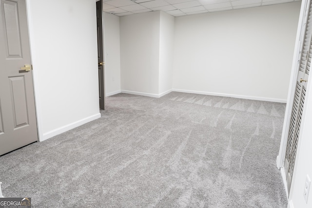 interior space featuring a paneled ceiling, carpet flooring, and baseboards