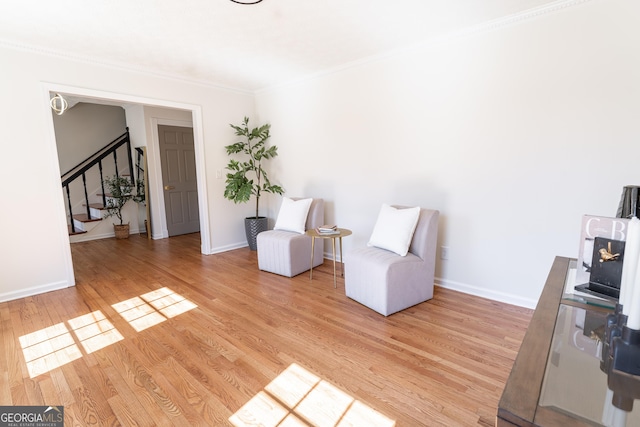 unfurnished room featuring light wood-style flooring, stairway, baseboards, and ornamental molding