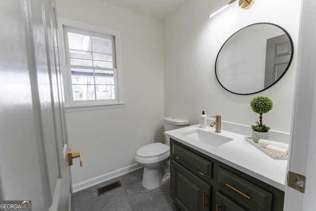 half bath with toilet, baseboards, visible vents, and vanity