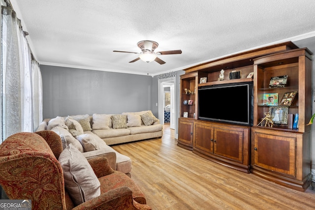 living room with light wood-type flooring, ceiling fan, a textured ceiling, and crown molding