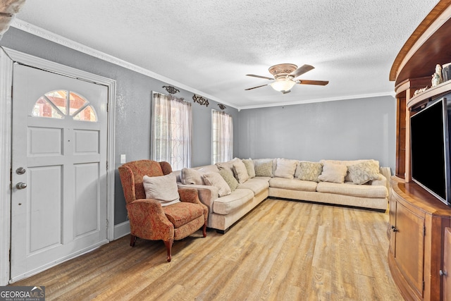 living area with a textured ceiling, ceiling fan, wood finished floors, and crown molding