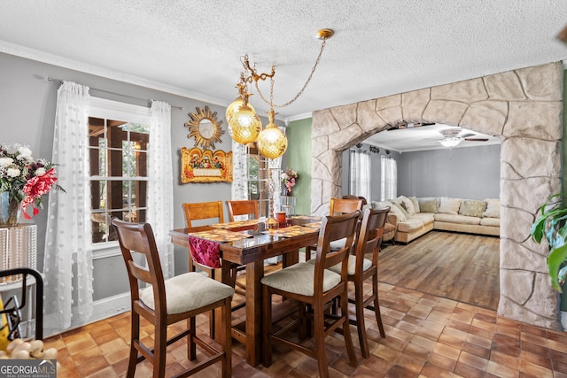 dining room featuring ornamental molding, arched walkways, and a textured ceiling