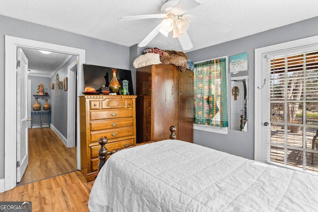 bedroom with a textured ceiling, wood finished floors, a ceiling fan, baseboards, and access to outside