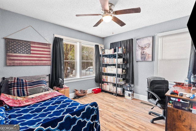 bedroom with a textured ceiling, ceiling fan, wood finished floors, and baseboards