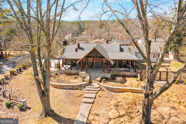 view of front of house with a porch, fence, a chimney, and a shingled roof