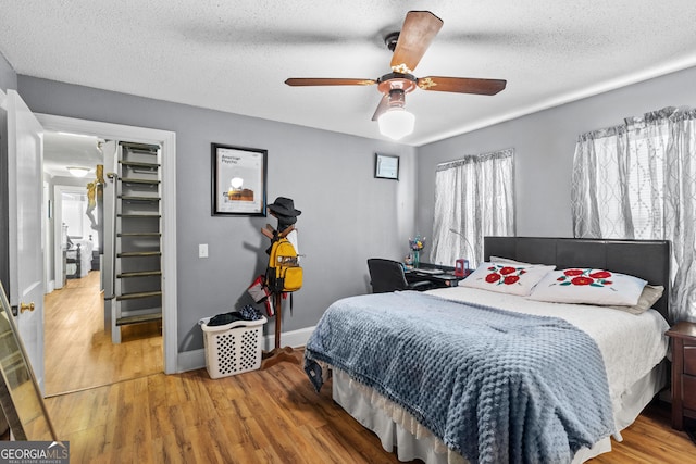 bedroom featuring a textured ceiling, ceiling fan, wood finished floors, and baseboards