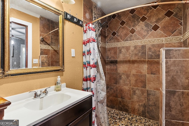 full bathroom featuring a textured wall, a shower stall, and vanity