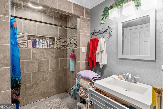 bathroom featuring vanity, a tile shower, crown molding, and a textured wall