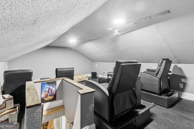 home theater featuring lofted ceiling, baseboards, a textured ceiling, and wood finished floors