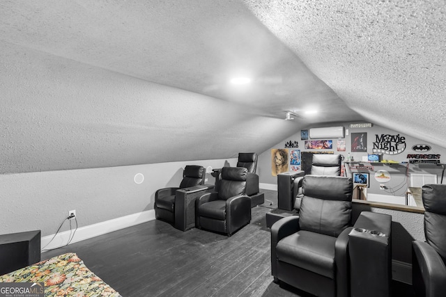 cinema room featuring baseboards, wood finished floors, vaulted ceiling, a textured ceiling, and an AC wall unit