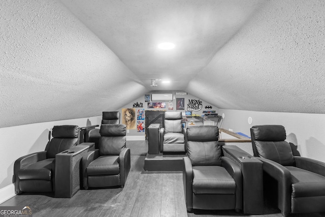 home theater with vaulted ceiling, a textured ceiling, wood finished floors, and baseboards