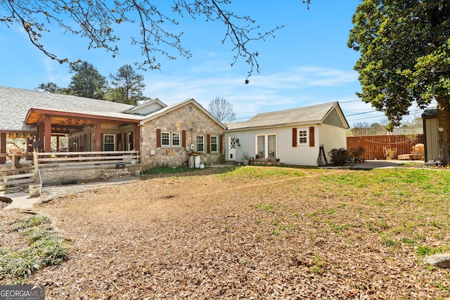 rear view of house with stone siding and fence