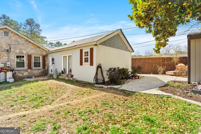 view of side of home featuring a yard, a patio, and fence