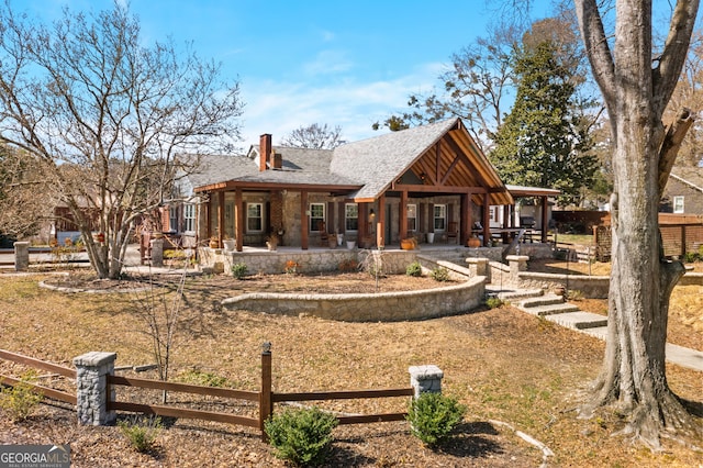 rear view of property featuring a fenced front yard and a chimney