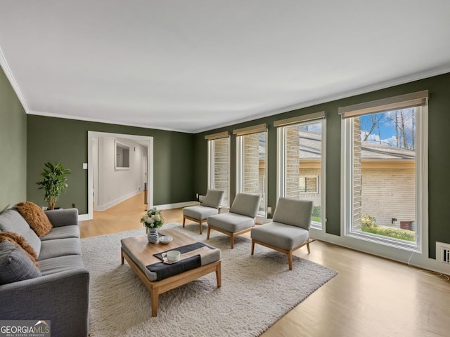 living room with light wood-type flooring, baseboards, and ornamental molding