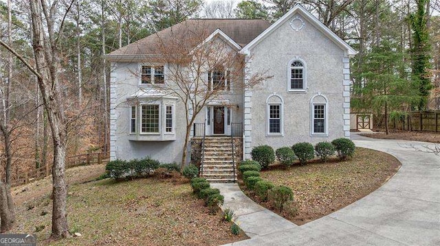 view of front facade with fence and stucco siding