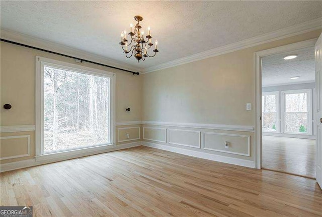 unfurnished dining area featuring a textured ceiling, ornamental molding, and light wood-type flooring