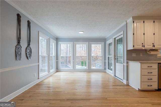 interior space with light wood-type flooring, a textured ceiling, baseboards, and crown molding