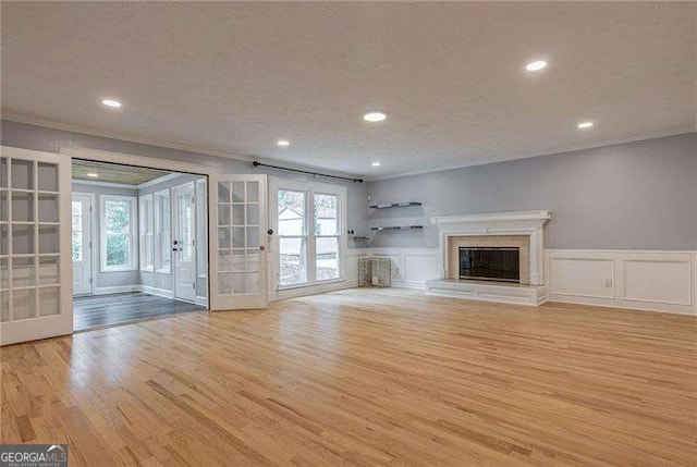 unfurnished living room with wood finished floors, crown molding, a decorative wall, and a premium fireplace