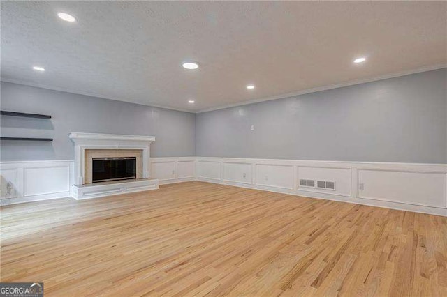 unfurnished living room with visible vents, a glass covered fireplace, wood finished floors, crown molding, and recessed lighting