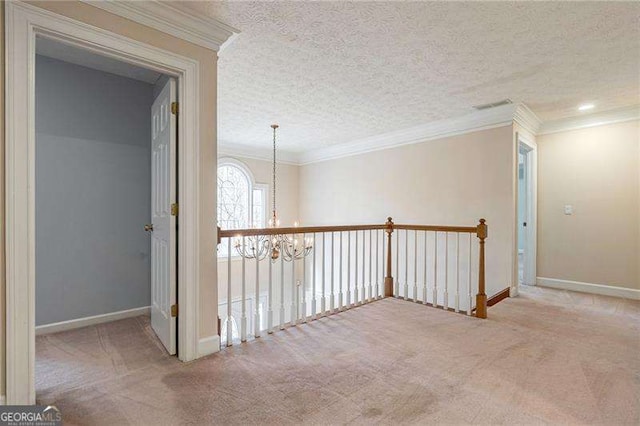 hall with a textured ceiling, crown molding, carpet flooring, and a notable chandelier