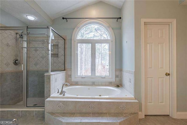 full bathroom featuring vaulted ceiling, a stall shower, plenty of natural light, and a jetted tub