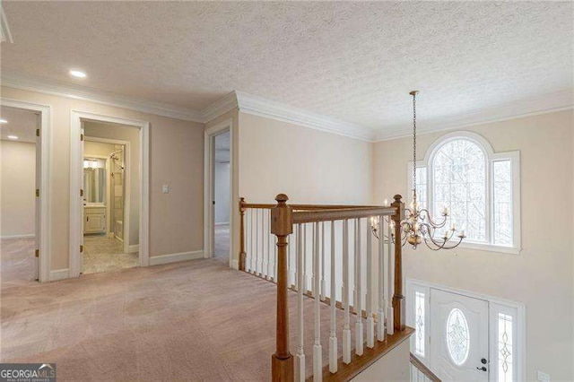 hallway featuring a chandelier, carpet flooring, crown molding, and a textured ceiling