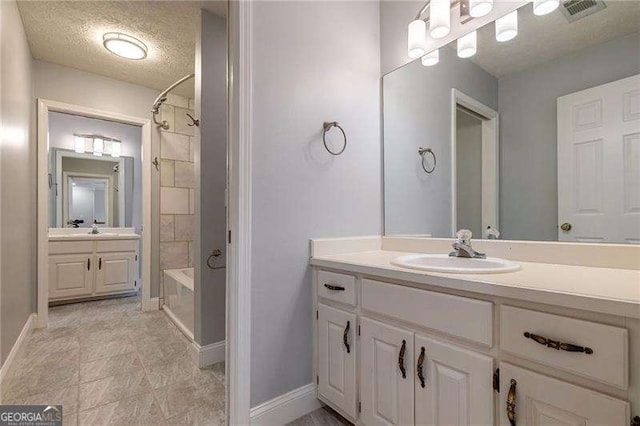 full bath with a textured ceiling, shower / bath combination, two vanities, a sink, and visible vents