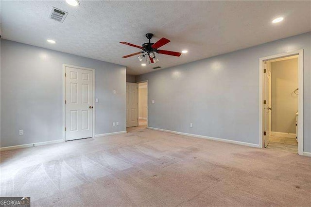 unfurnished room featuring baseboards, visible vents, light colored carpet, ceiling fan, and a textured ceiling