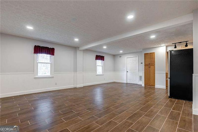 interior space with a wainscoted wall, a textured ceiling, and fridge