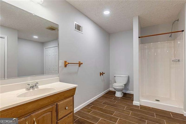 bathroom featuring visible vents, toilet, wood tiled floor, vanity, and walk in shower