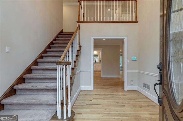 entrance foyer with a high ceiling, wood finished floors, visible vents, baseboards, and stairway