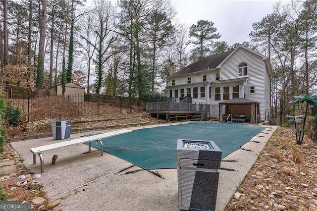 view of swimming pool with a deck, a patio area, fence, and a covered pool