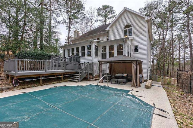 rear view of property featuring a patio, a chimney, a gazebo, fence, and a deck