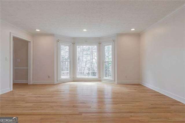 spare room featuring light wood-style floors, crown molding, and a textured ceiling