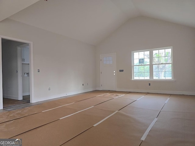 unfurnished living room featuring vaulted ceiling, baseboards, and basketball hoop