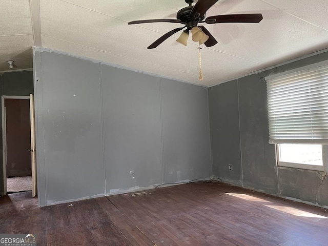 spare room featuring ceiling fan, vaulted ceiling, wood finished floors, and a textured ceiling