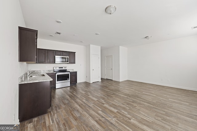 kitchen with visible vents, open floor plan, wood finished floors, stainless steel appliances, and dark brown cabinetry