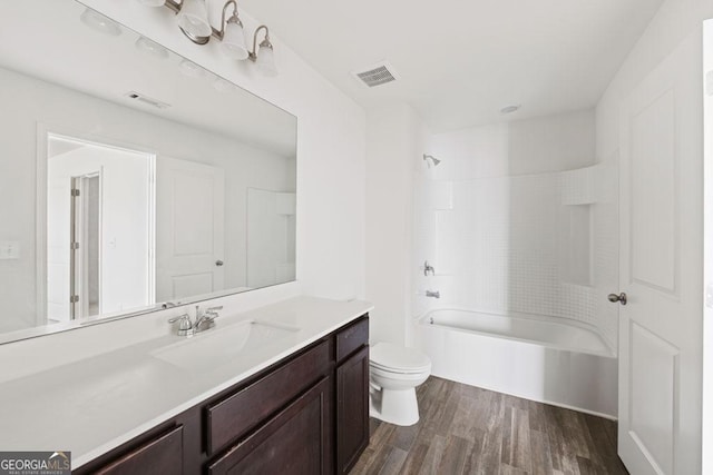 full bathroom featuring vanity, washtub / shower combination, wood finished floors, visible vents, and toilet