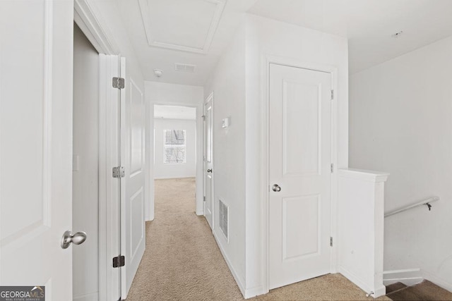 hallway with visible vents, light carpet, and baseboards