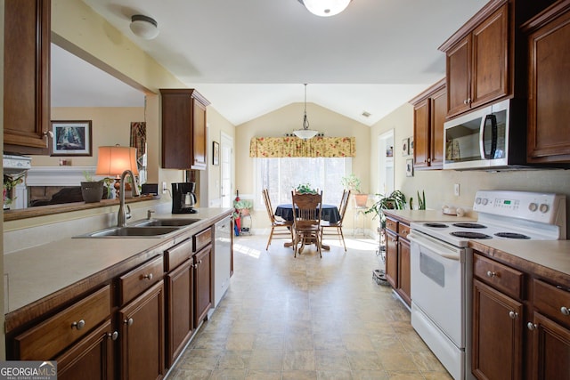 kitchen featuring a sink, decorative light fixtures, white appliances, light countertops, and vaulted ceiling